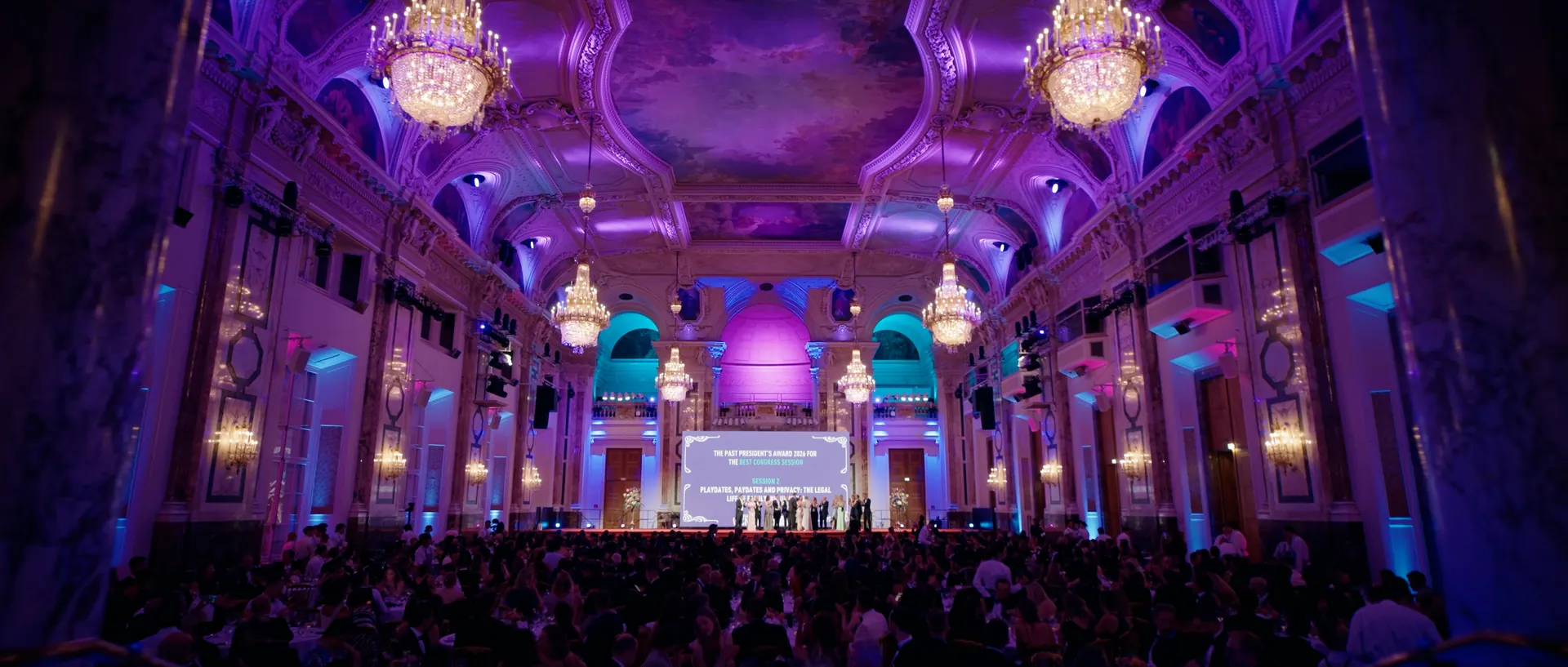 Festsaal in violettem Licht, das Publikum vor der Bühne
