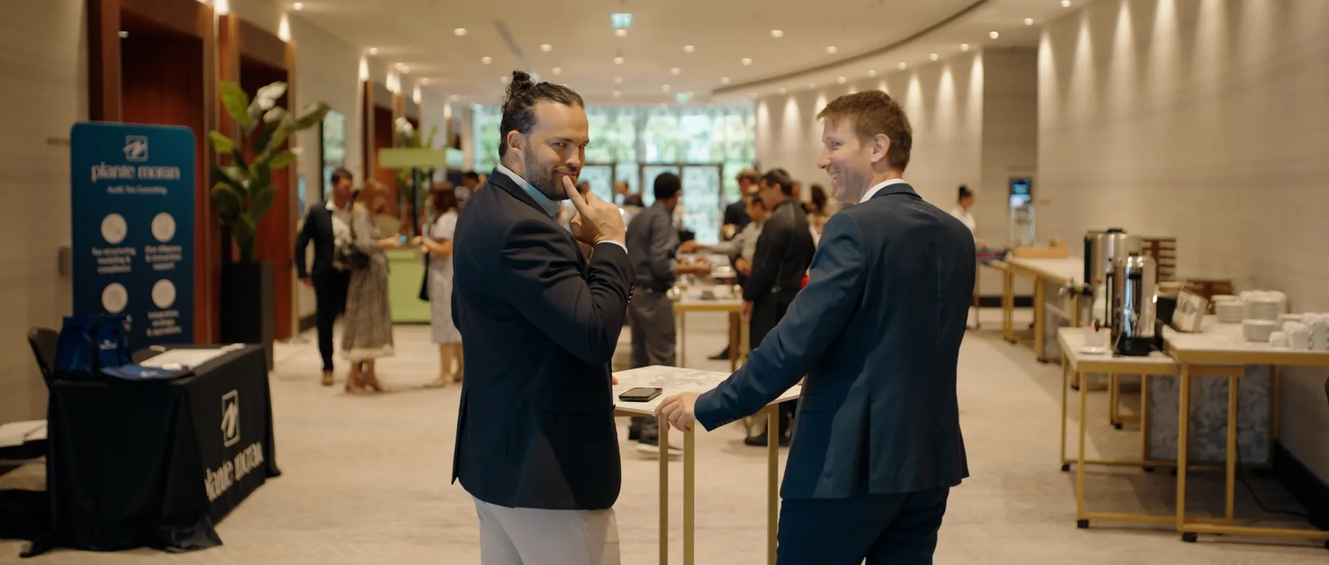 Zwei Männer in Anzügen im Gespräch neben einem Ausstellerstand im Foyer