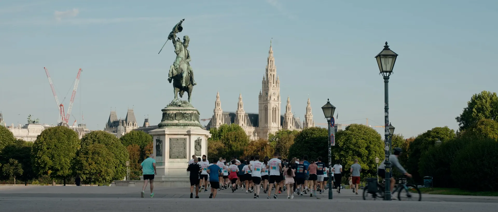 Reiterstandbild vor den Türmen des Wiener Rathauses, davor eine Laufgruppe