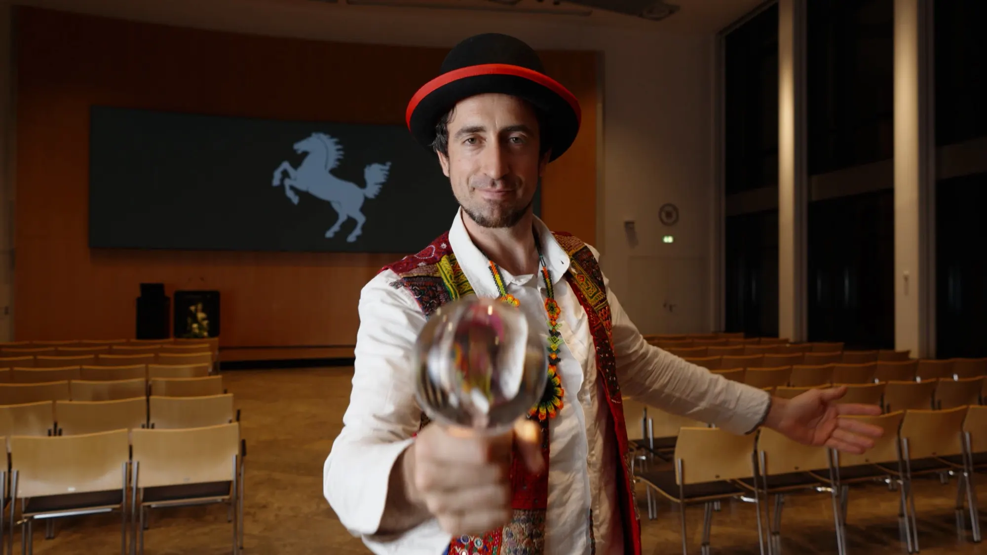 Fabian Seewald mit Melone hält eine Glaskugel in die Kamera, dahinter das Stuttgarter Rössle