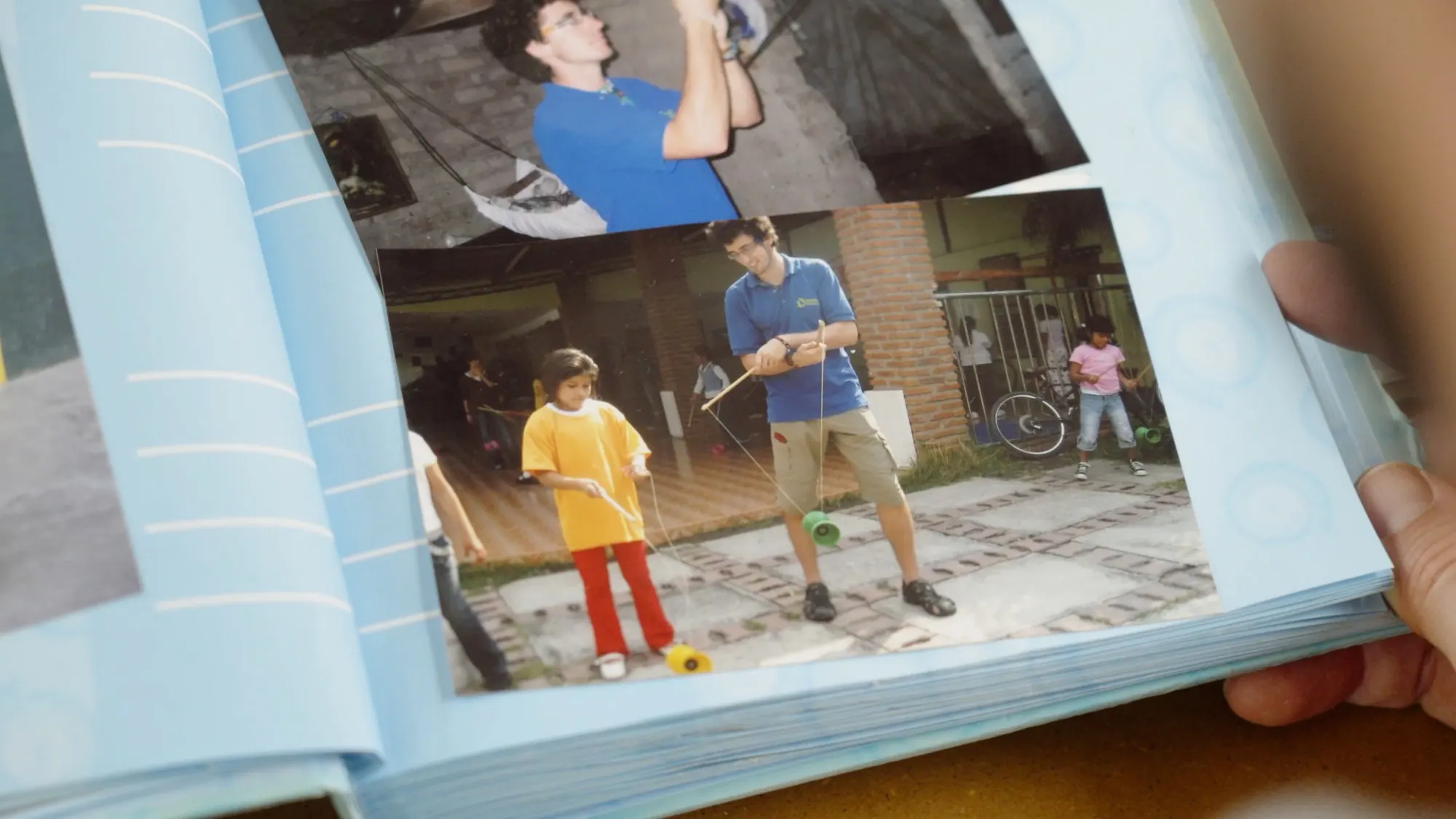 Hände blättern in einem Fotoalbum mit Aufnahmen von Jonglage-Workshops
