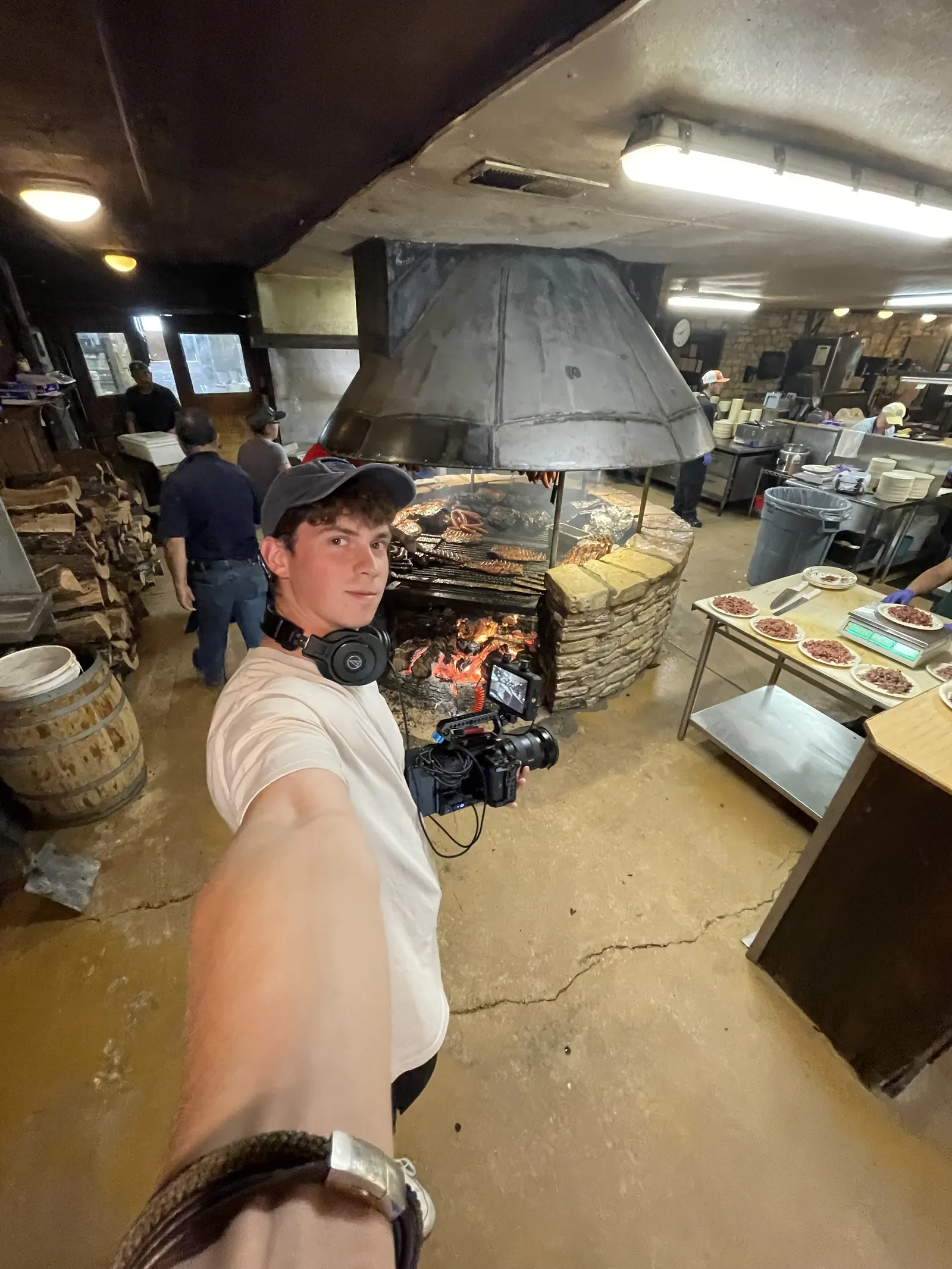 Ausgestreckter Arm mit Kamera in einer Restaurantküche mit Holzofen