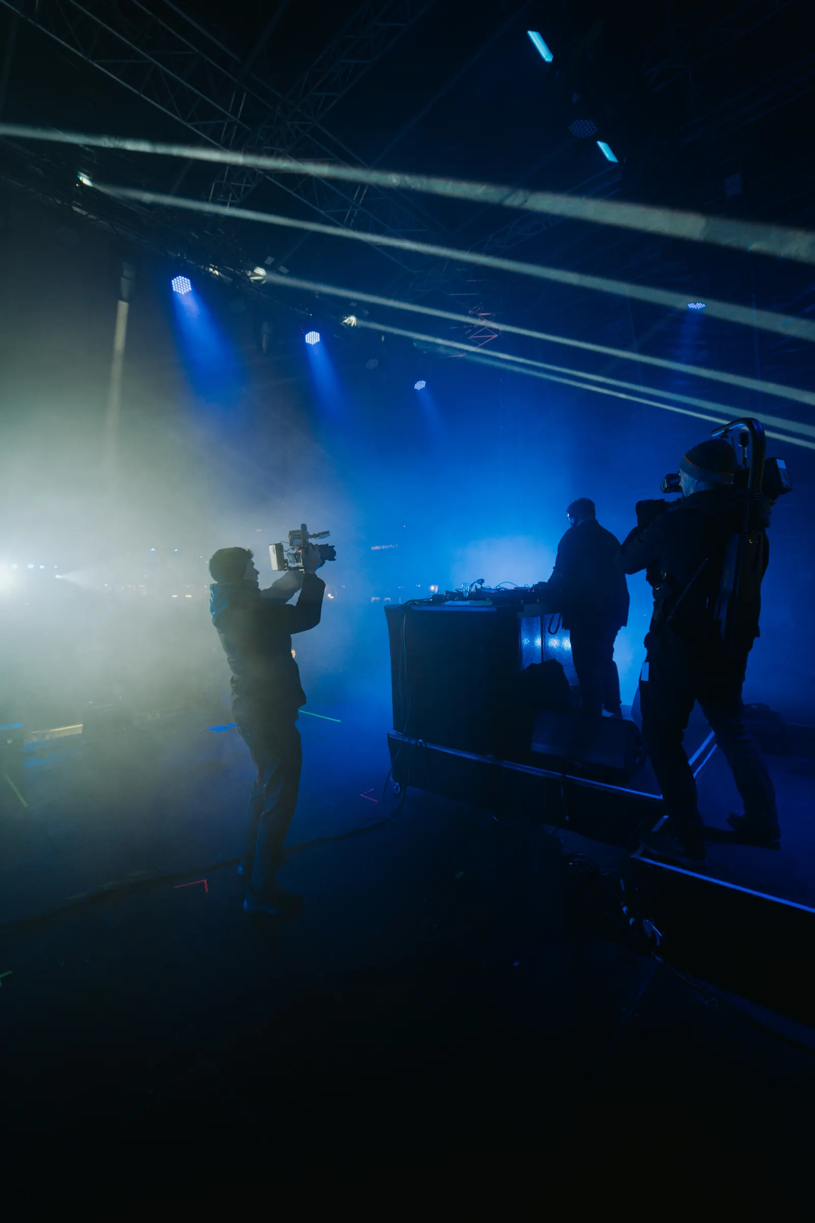 Kameramann im blauen Bühnenlicht neben dem DJ-Pult