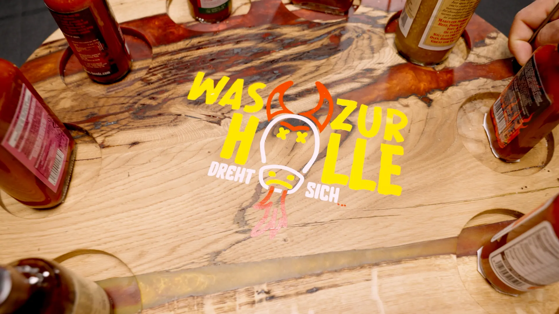 Holzbrett mit Saucenflaschen und dem Logo der Sendung